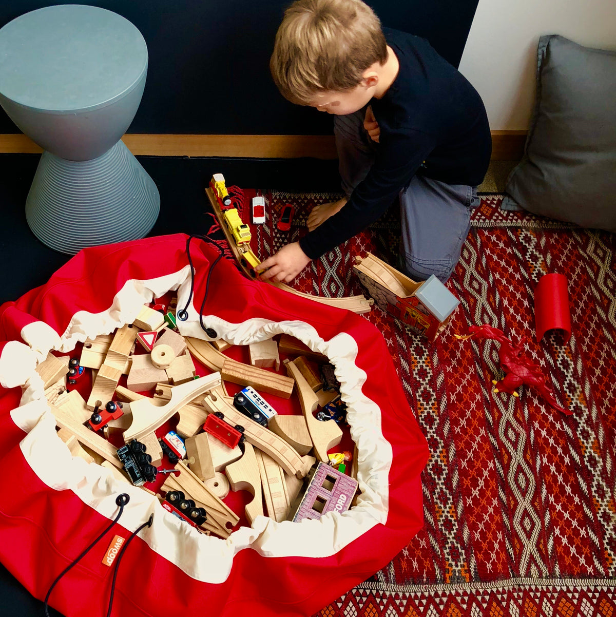 red toy storage bag with wooden trains
